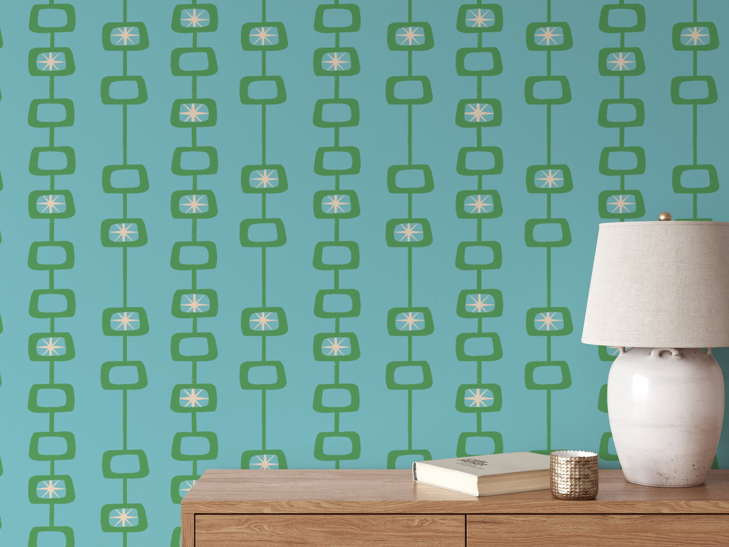 Mid Century Atomic Orbs wallpaper in green and teal behind a wood console with a cream ceramic lamp