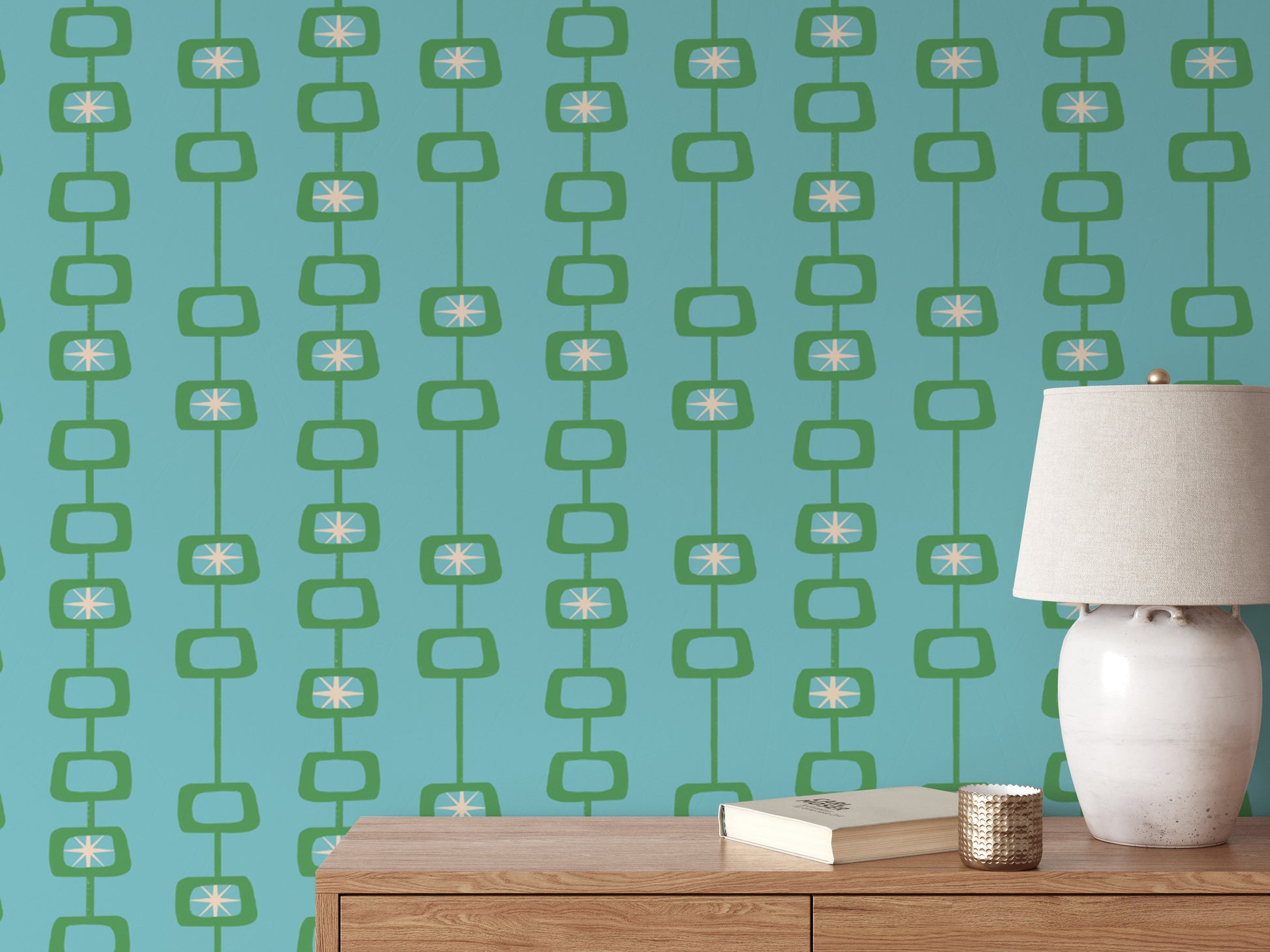 Mid Century Atomic Orbs wallpaper in green and teal behind a wood console with a cream ceramic lamp