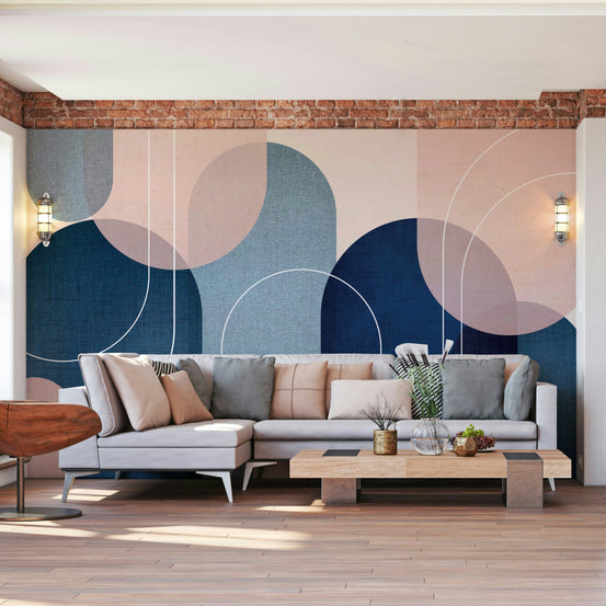 Mid-Century Modern Arches wallpaper mural in navy blue and blush behind a gray sectional in a brick living room