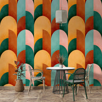 Mid Mod Geometry Sunburn wallpaper mural behind a white bistro table with woven rattan chairs and a rubber plant