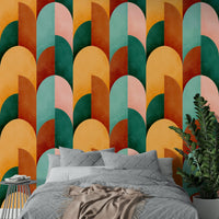 Mid Mod Geometry Sunburn wallpaper mural above a bed with grey quilted bedding and a eucalyptus plant nearby