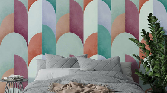 Mid Mod Geometry Sundown wallpaper mural in pastel mint and mauve arches above a bed with grey quilted bedding