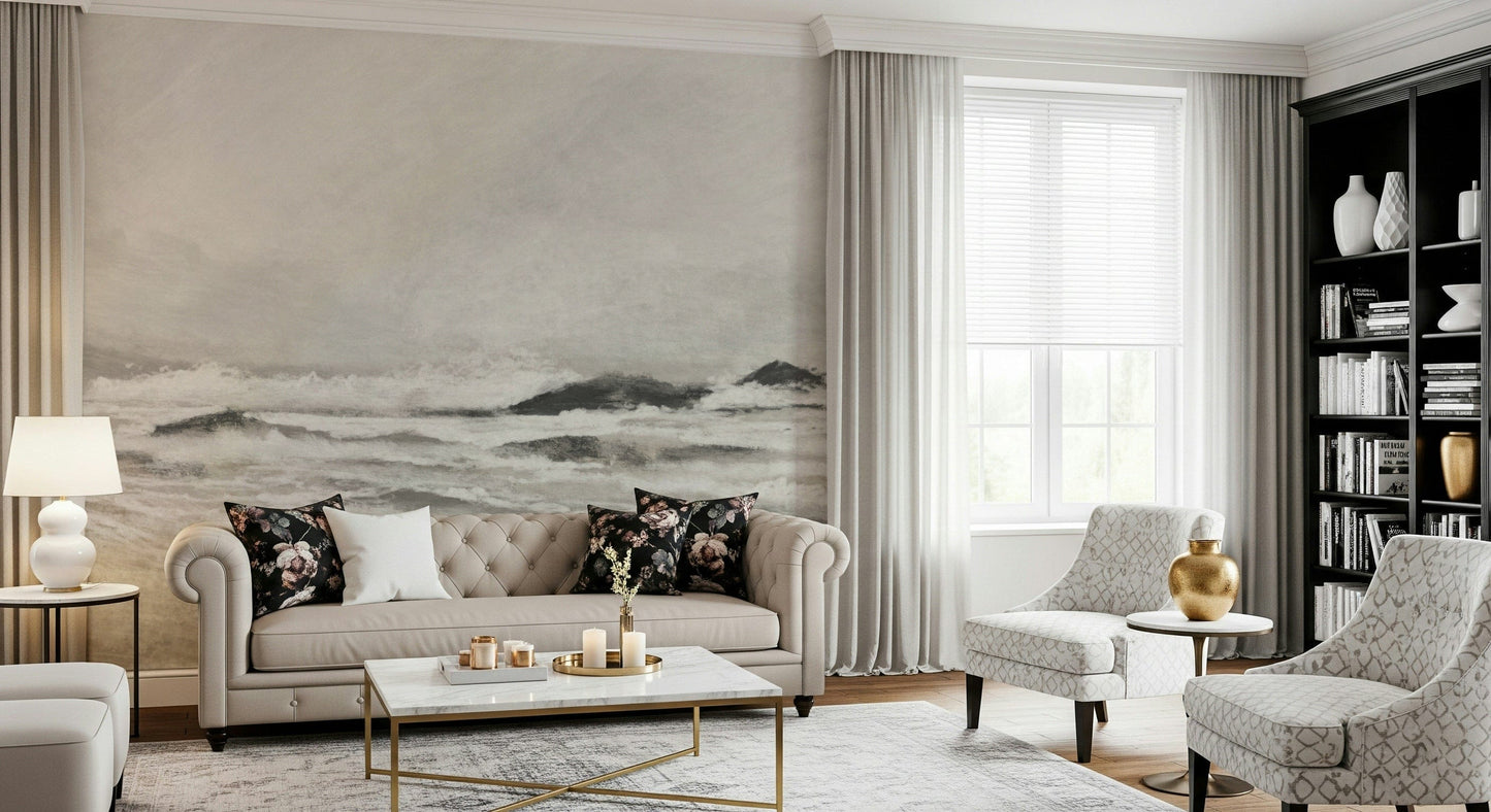 Misty Coast wallpaper mural in warm grey behind a beige tufted Chesterfield sofa with floral cushions in a living room