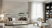 Misty Coast wallpaper mural in warm grey behind a beige tufted Chesterfield sofa with floral cushions in a living room