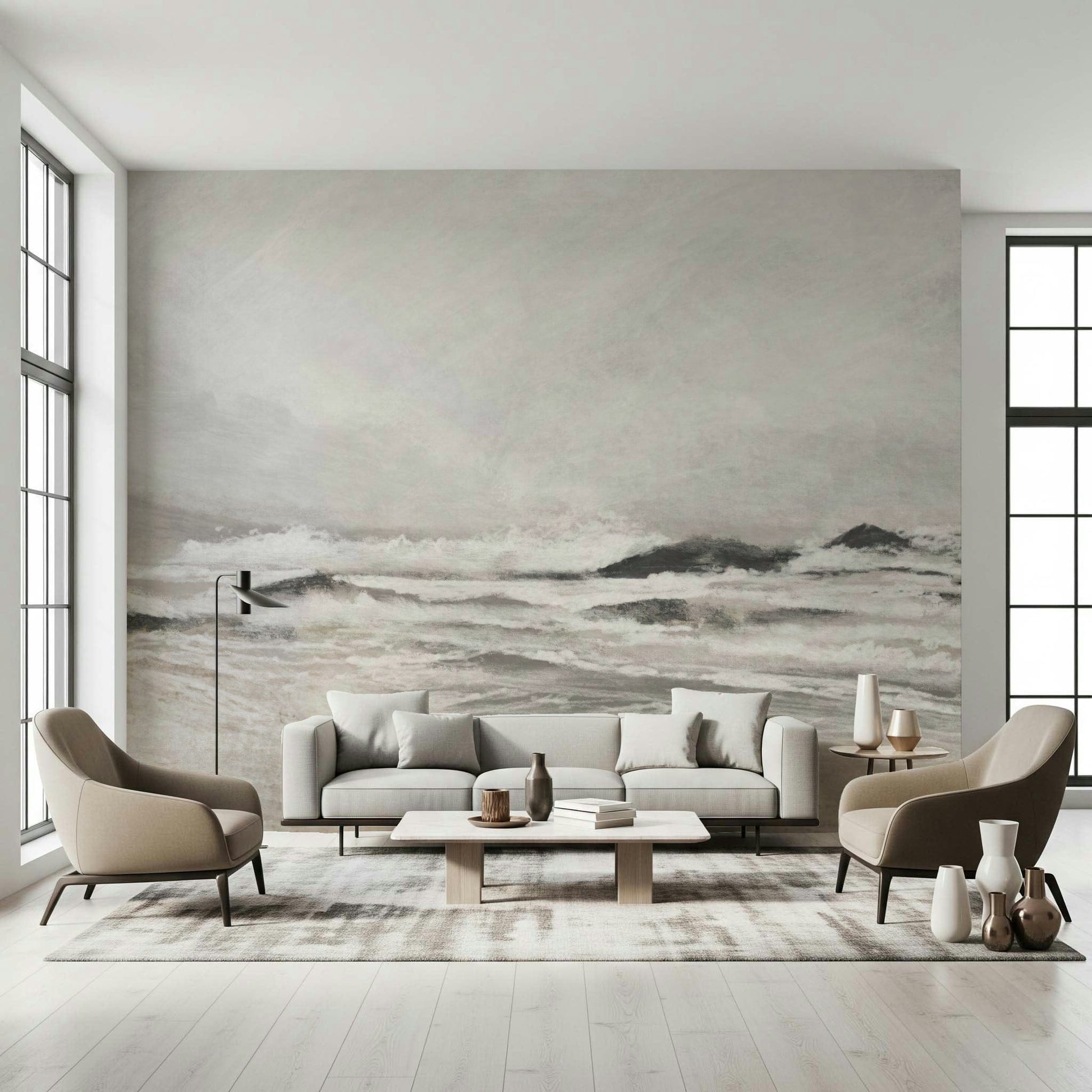 Misty Coast wallpaper mural of a pale stormy sea behind a grey sofa and two taupe armchairs in a bright living room