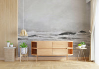 Misty Coast wallpaper mural of a grey seascape behind a light oak sideboard and potted plants in a living room