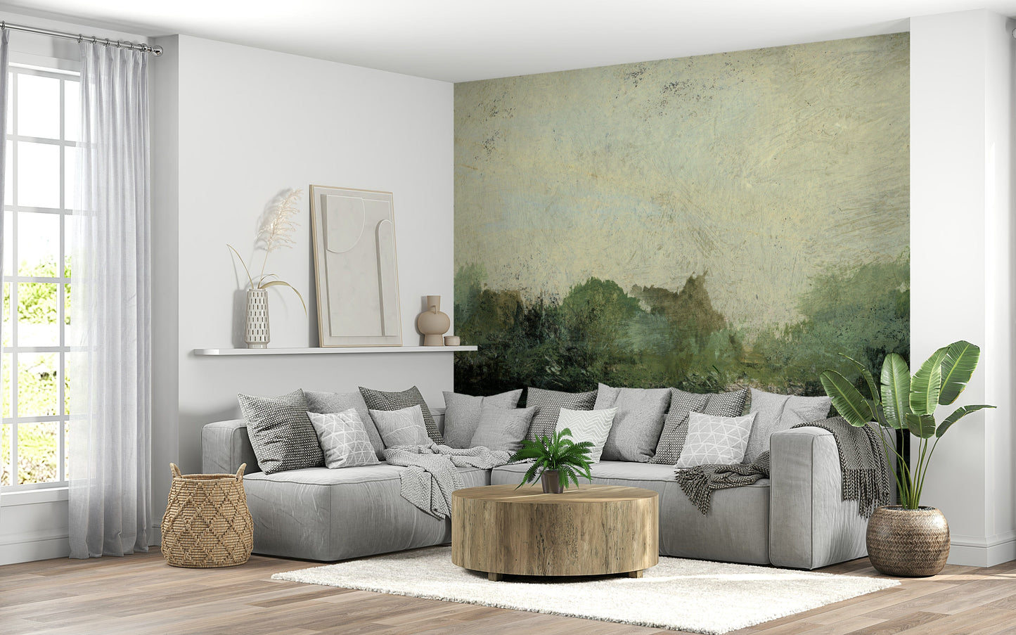 Misty Glen wallpaper mural of green woodland behind a grey sectional and round wood coffee table