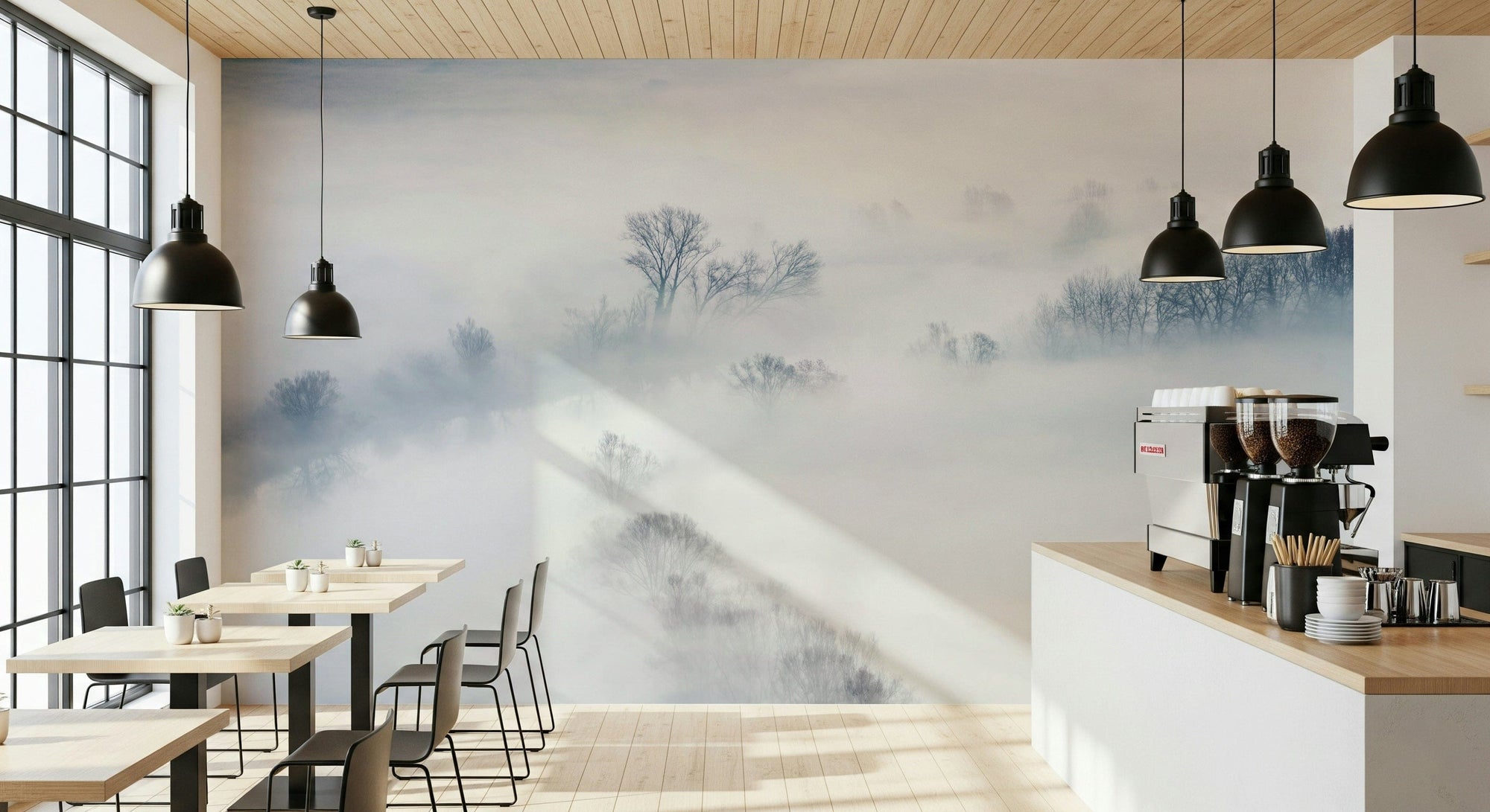 Misty Treescape wallpaper mural of foggy winter trees behind small wood cafe tables and a coffee bar with pendant lamps
