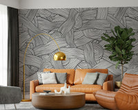 Monochromatic Striped Maze wall mural of woven lines behind a tan leather sofa in a living room