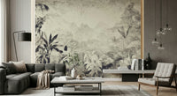 Monochrome Jungle Dream wallpaper mural in grey tropical foliage behind a grey sectional and cream armchair living room