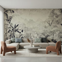 Monochrome Jungle Dream wallpaper mural of grey tropical leaves behind a cream sectional and terracotta accent chairs