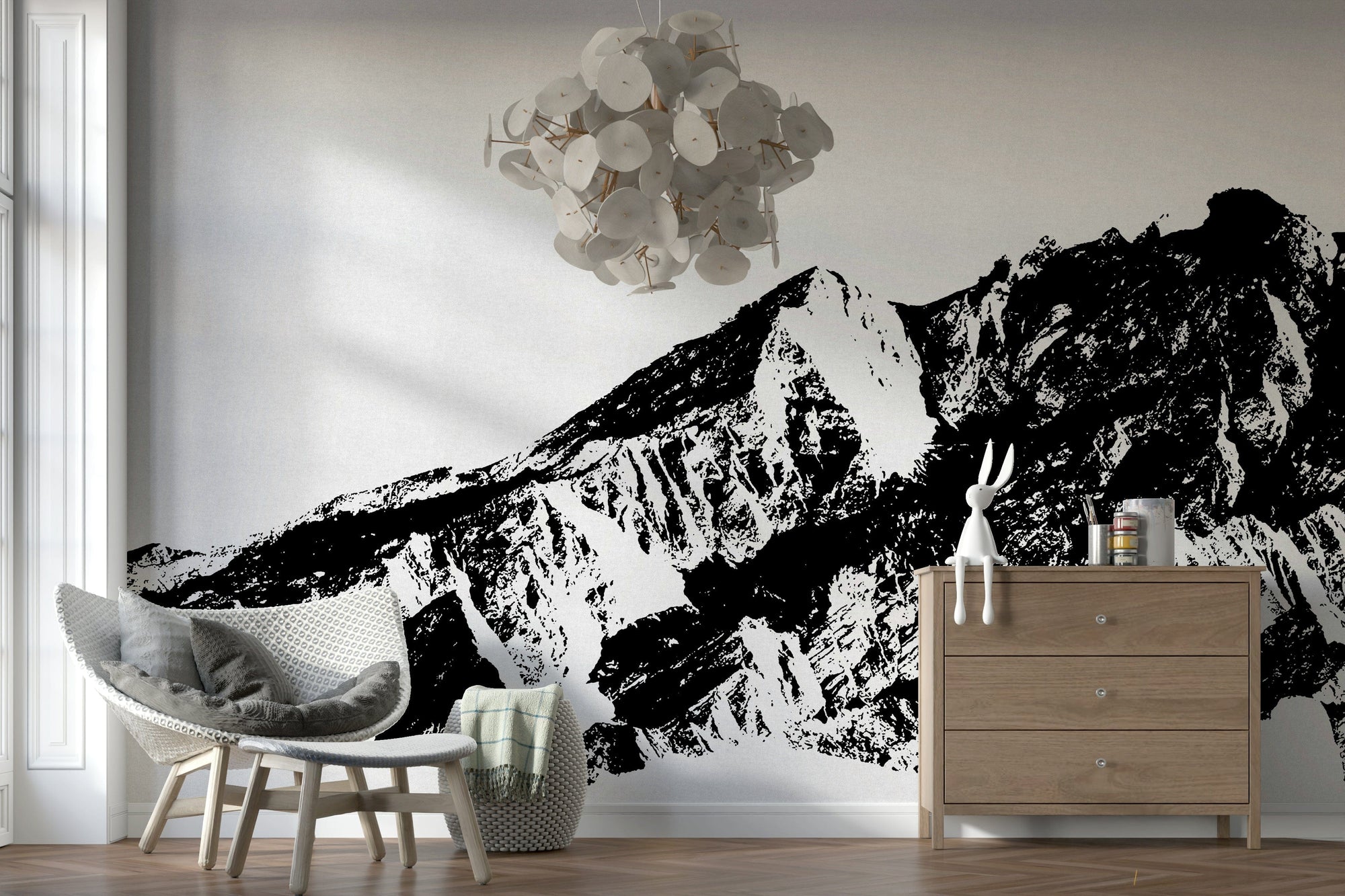 Monochrome Majesty wallpaper mural of a black and white mountain range behind a white rattan chair and wood dresser in a lounge
