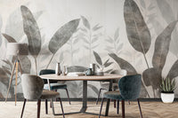 Monochrome Tropical Leaves wall mural behind an oval dining table with grey and teal velvet chairs