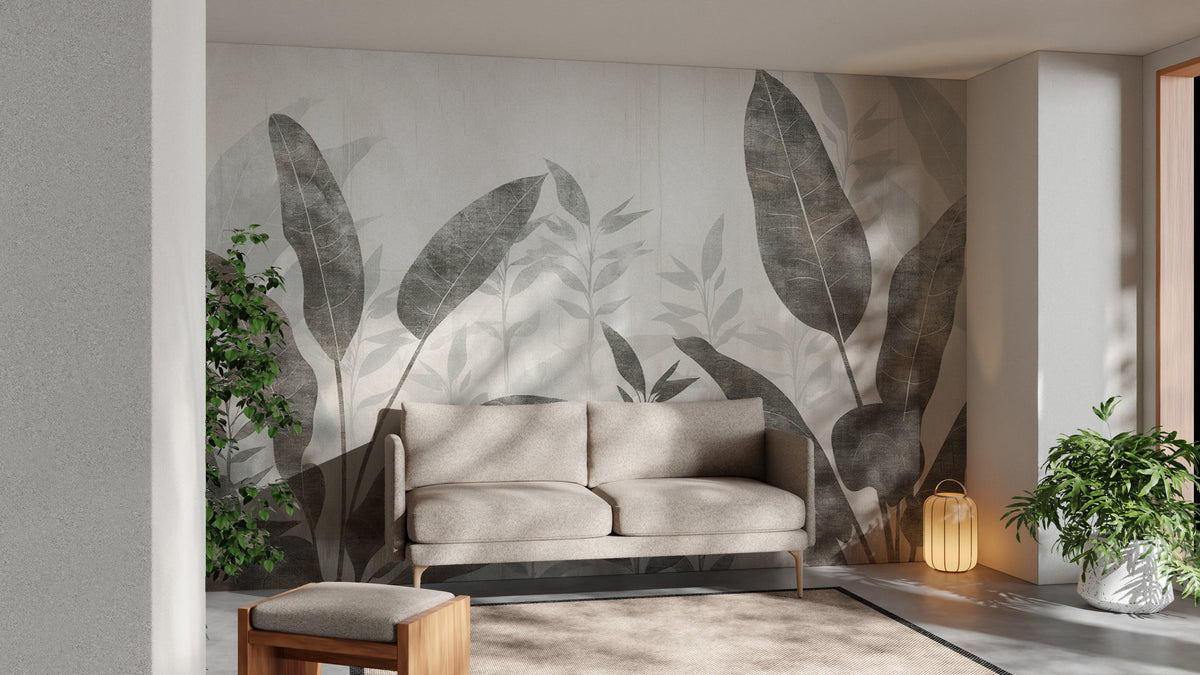 Monochrome Tropical Leaves wall mural behind a beige sofa with potted plants and a lantern lamp