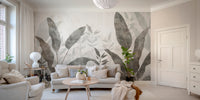 Monochrome Tropical Leaves wall mural behind a grey sofa and round wood table in a bright living room