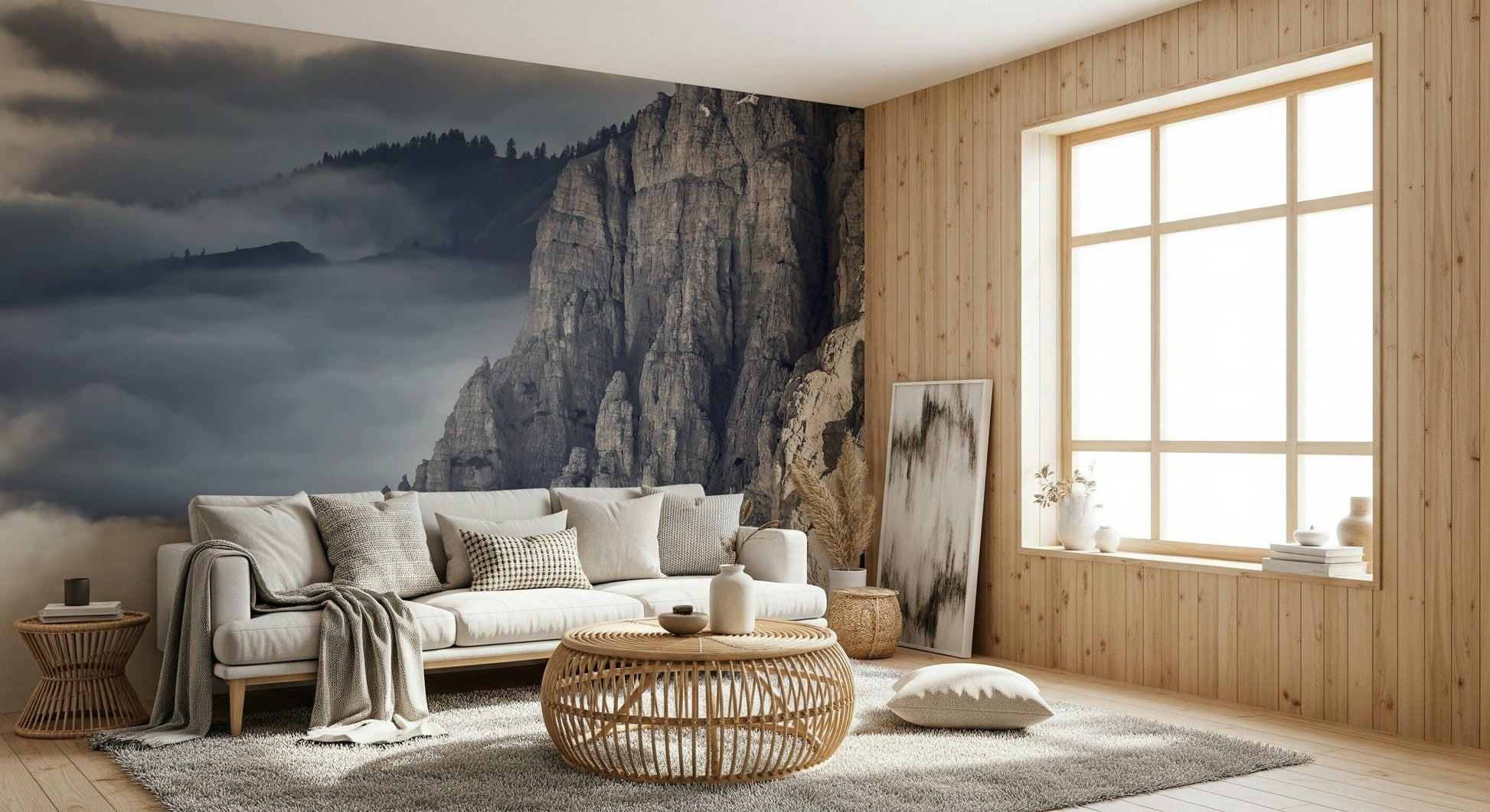 Mountain Majesty wallpaper mural of misty grey peaks behind a cream sofa and rattan table in a living room