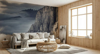 Mountain Majesty wallpaper mural of misty grey peaks behind a cream sofa and rattan table in a living room