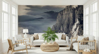 Mountain Majesty wallpaper mural of cloudy mountain cliffs behind white sofas and a palm in a sunny living room