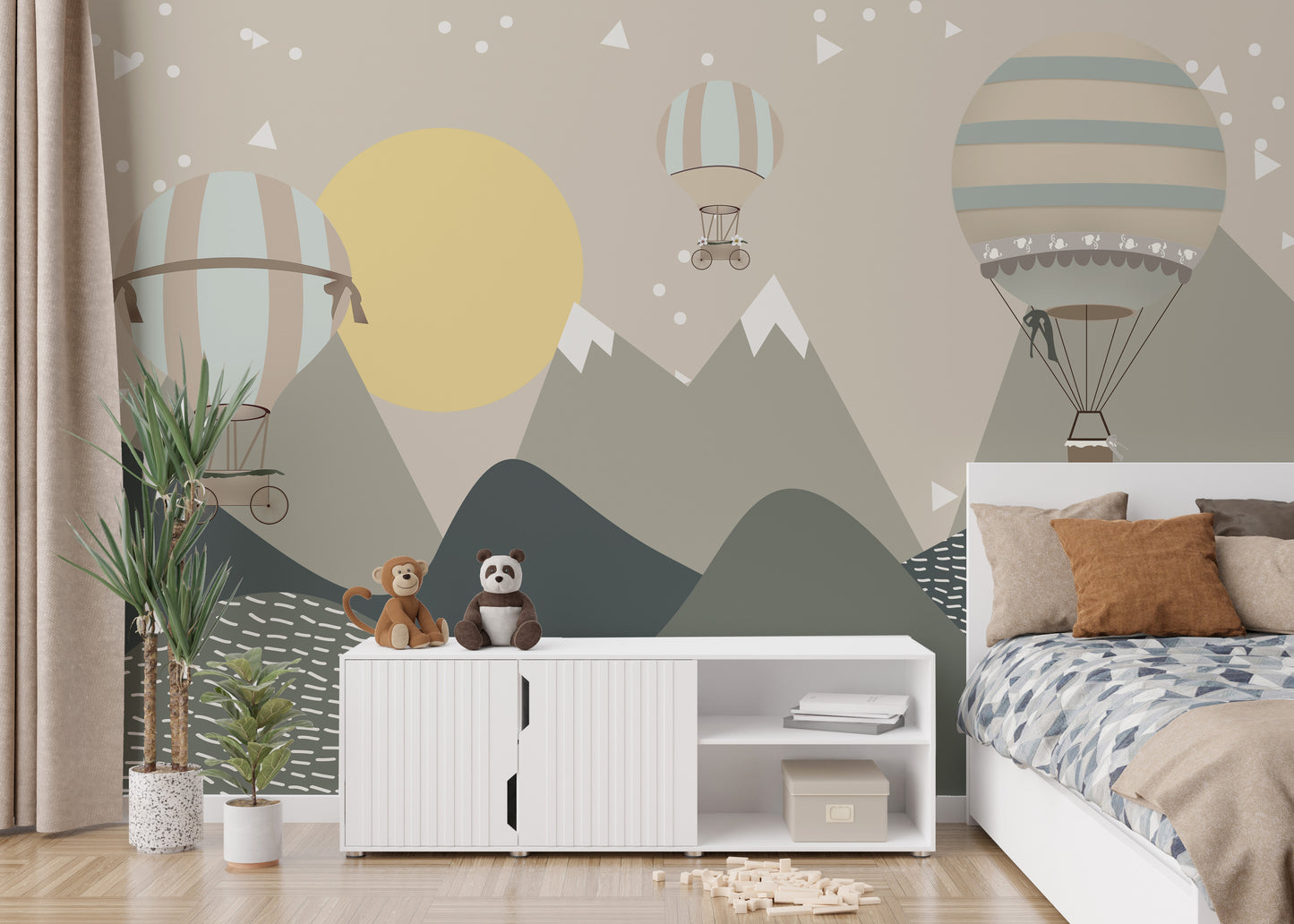 Mountains and Hot Air Balloons wallpaper in muted green behind a white kids bed with rust pillows and plush toys