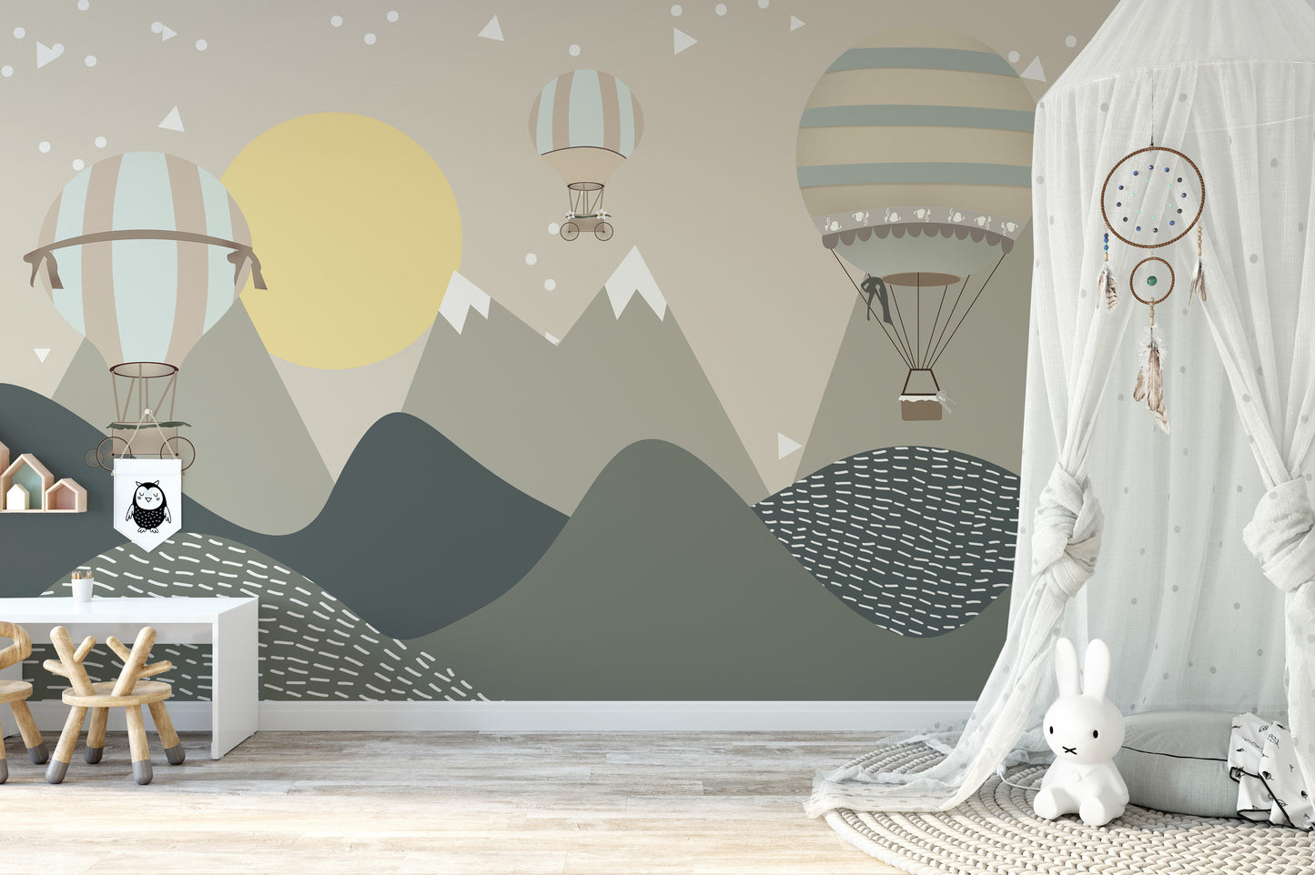 Mountains and Hot Air Balloons wallpaper in scandi green with a yellow sun behind a white play desk and bunny toy in a nursery