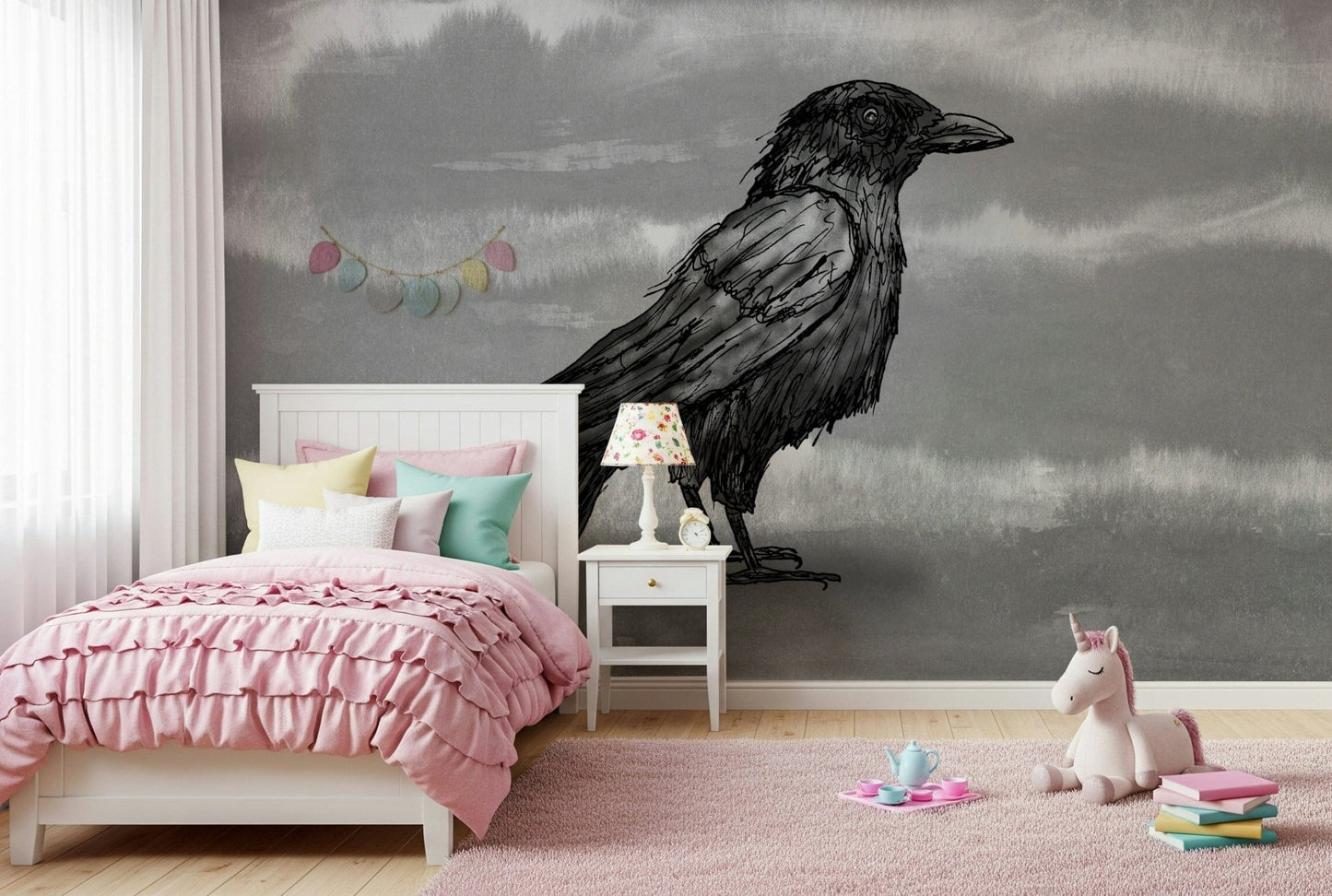 Mr Crow wall mural of an ink raven on grey behind a wood desk and bed in a kids bedroom