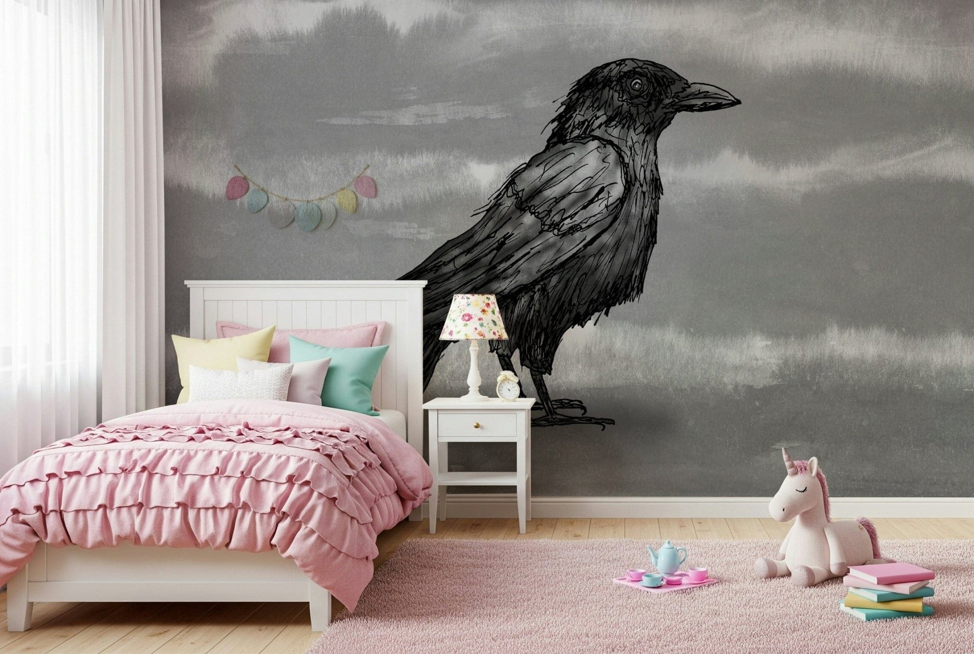 Mr Crow wall mural of an ink raven on grey behind a wood desk and bed in a kids bedroom