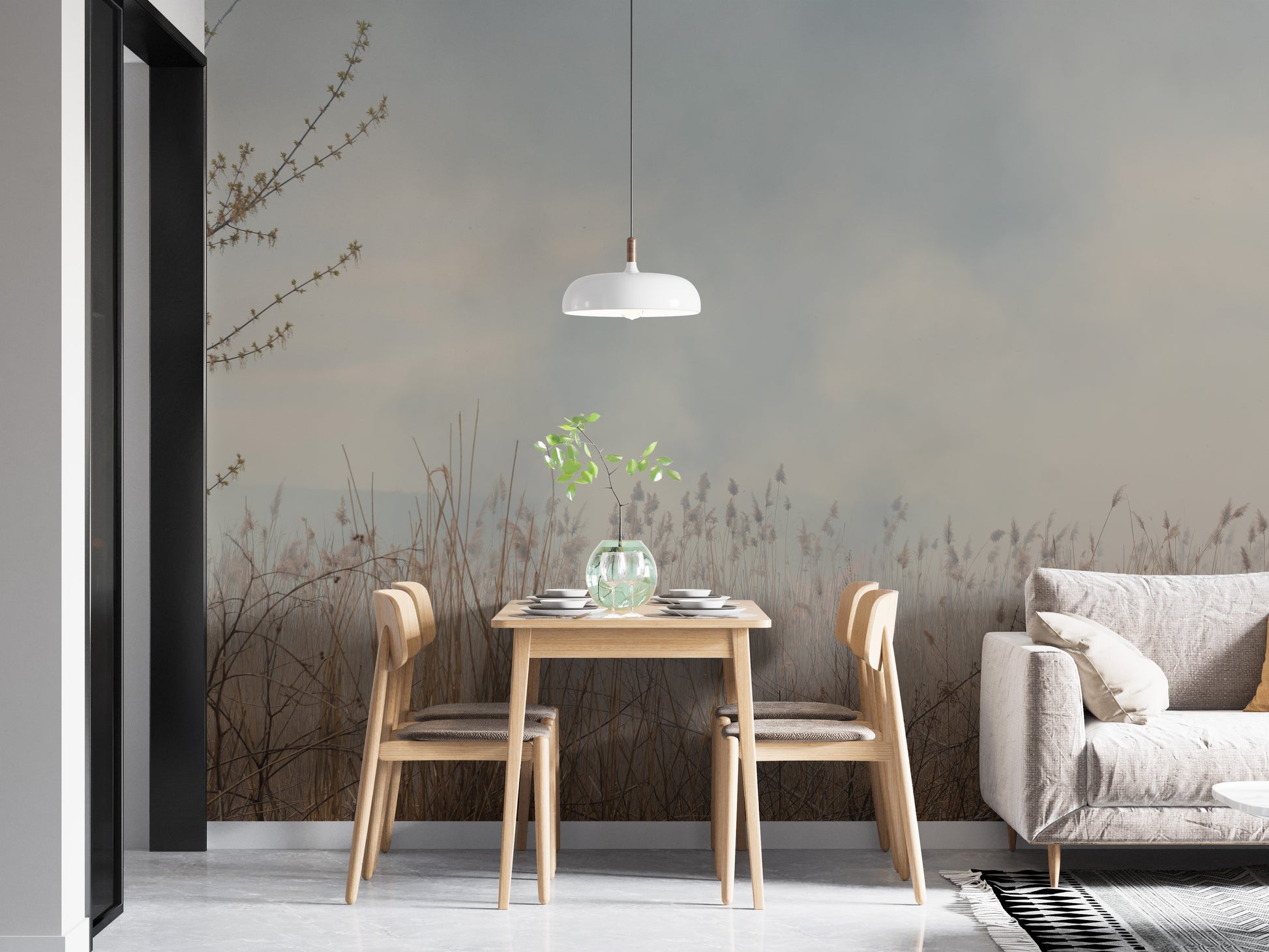Natural Reeds wallpaper mural of misty grasses behind a wood dining table and gray sofa in a dining nook