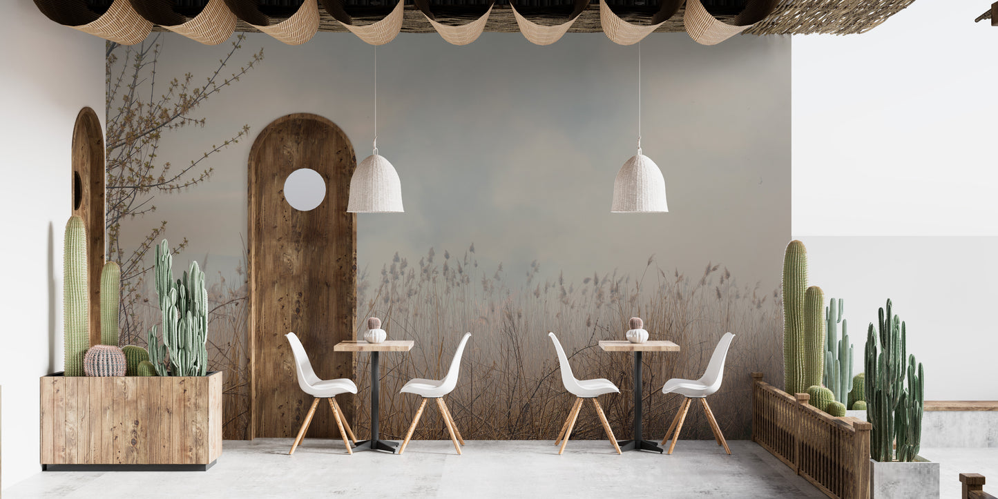 Natural Reeds wallpaper mural of misty beige grasses on gray behind white cafe chairs and wood tables