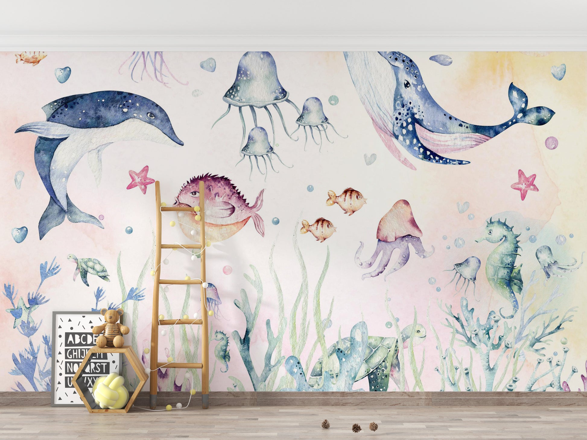 Nautical Creatures wall mural with watercolour whale and dolphin behind a wood ladder and teddy bear in a kids room