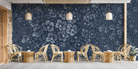 Navy Blue Garden Flower wallpaper mural behind wicker chairs and tables in a cafe seating area