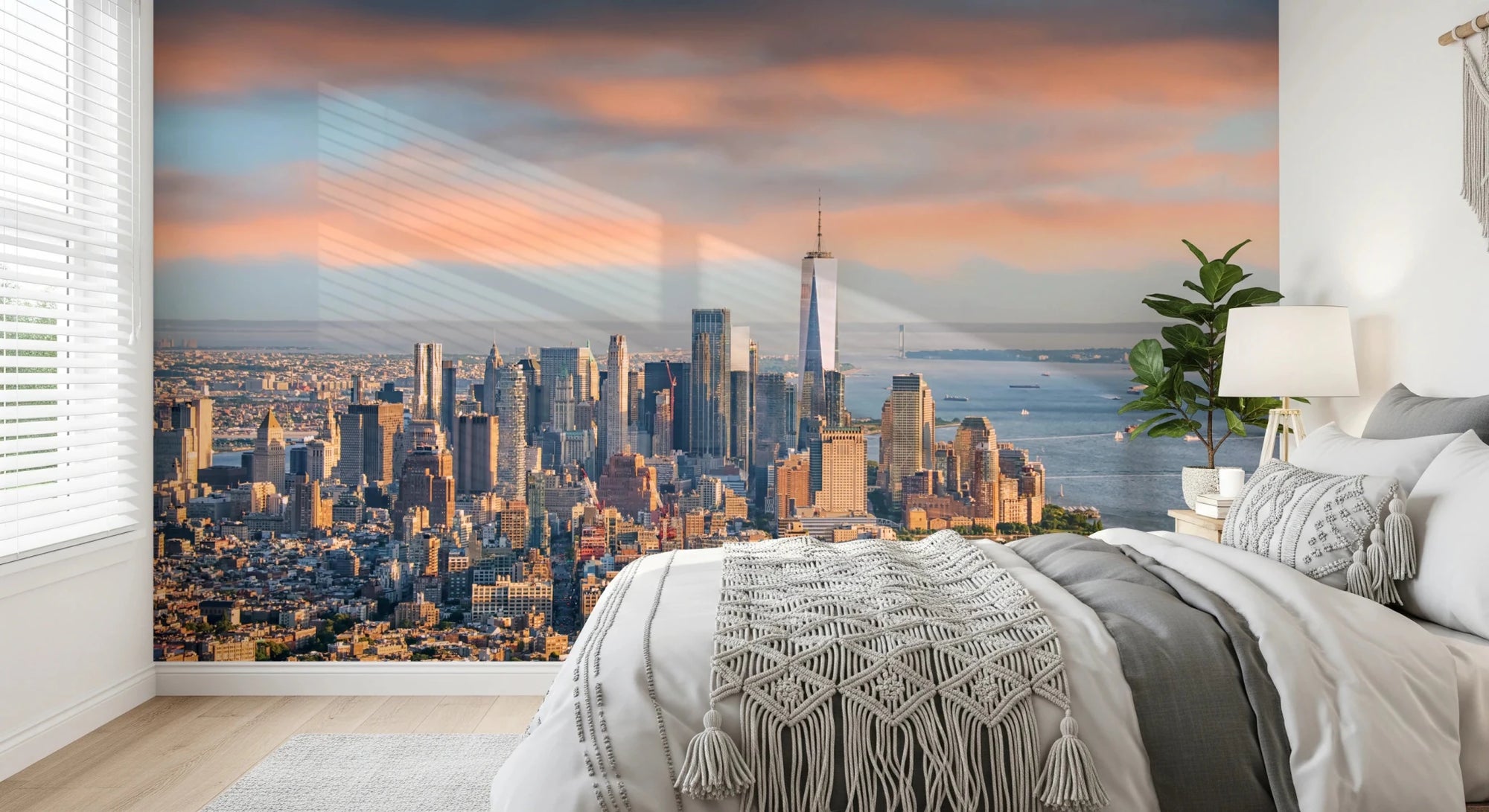 New York Dawn wallpaper mural of the Manhattan skyline at dawn behind a white bed with a macrame throw in a bedroom