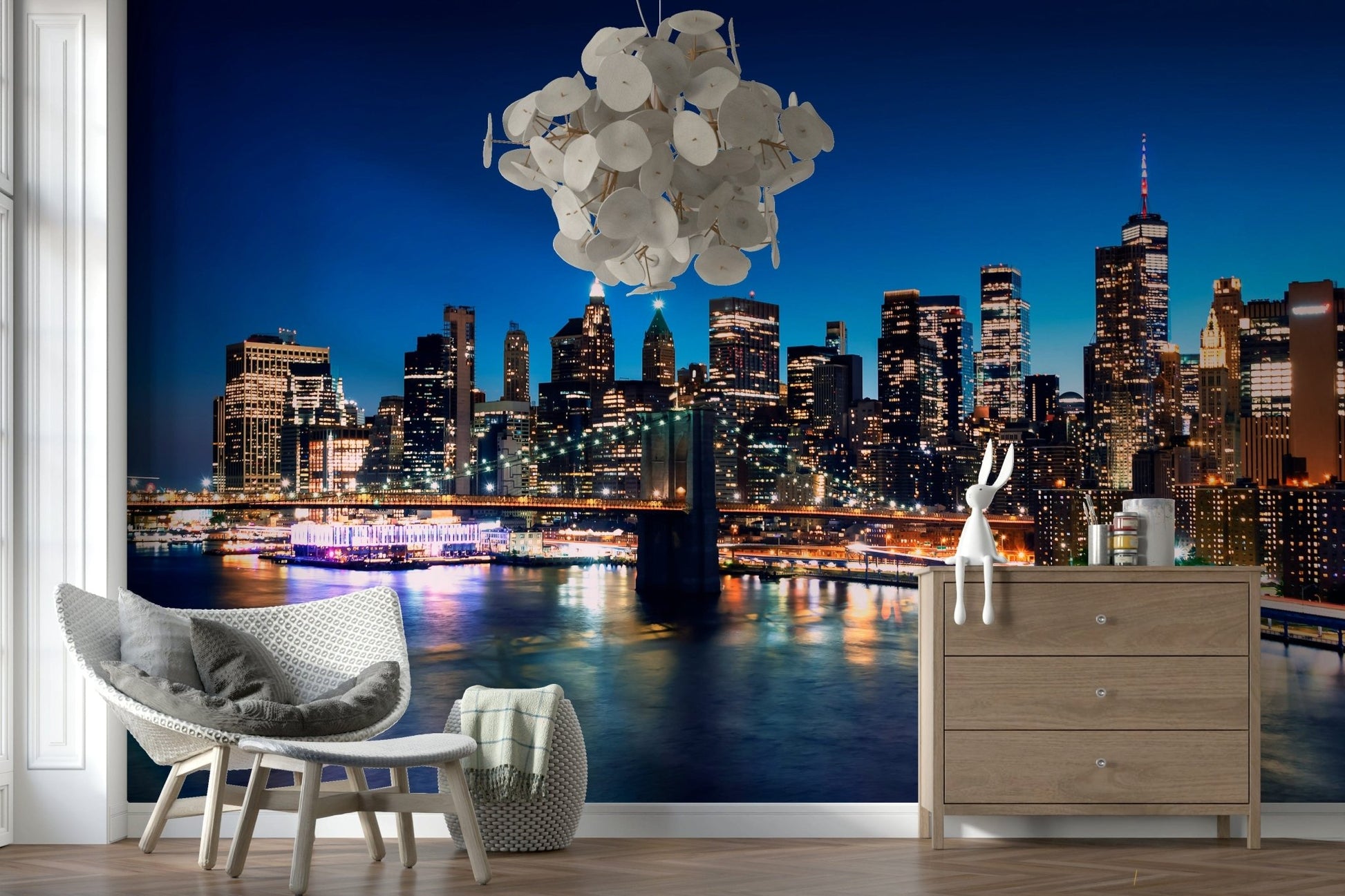 Night Metropolis wallpaper mural of the city at night behind a grey rattan armchair and wood dresser in a living room