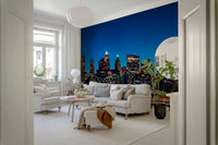 Night Metropolis wallpaper mural of the night cityscape behind a white sofa and armchair in a Scandinavian living room
