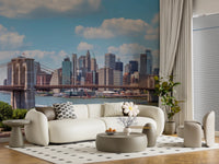 NYC Bridge Vista wallpaper mural of the blue-sky city skyline behind a cream curved sofa in a living room