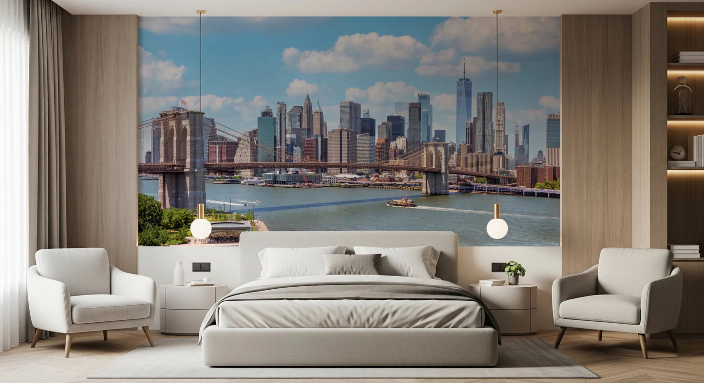 NYC Bridge Vista wallpaper mural of the Manhattan skyline above a grey bed framed by two white armchairs in a bedroom