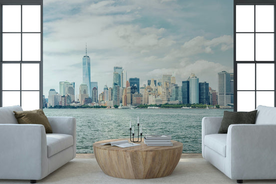 NYC Skyline View wallpaper mural of Lower Manhattan across the harbor between two white armchairs in a living room