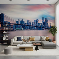 NYC Twilight Dreams wallpaper mural of the pink twilight skyline behind a grey sectional sofa and shelving