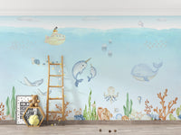 Ocean Explorer Watercolor wallpaper with narwhals, octopus and coral behind a wooden ladder and teddy bear