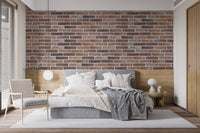 Old Dirty Red Brick wallpaper mural behind a grey upholstered bed and woven armchair in a cozy bedroom
