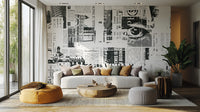 Urban Newsprint wallpaper mural of black-and-white newspaper collage behind a grey sofa and mustard pouf in a living room