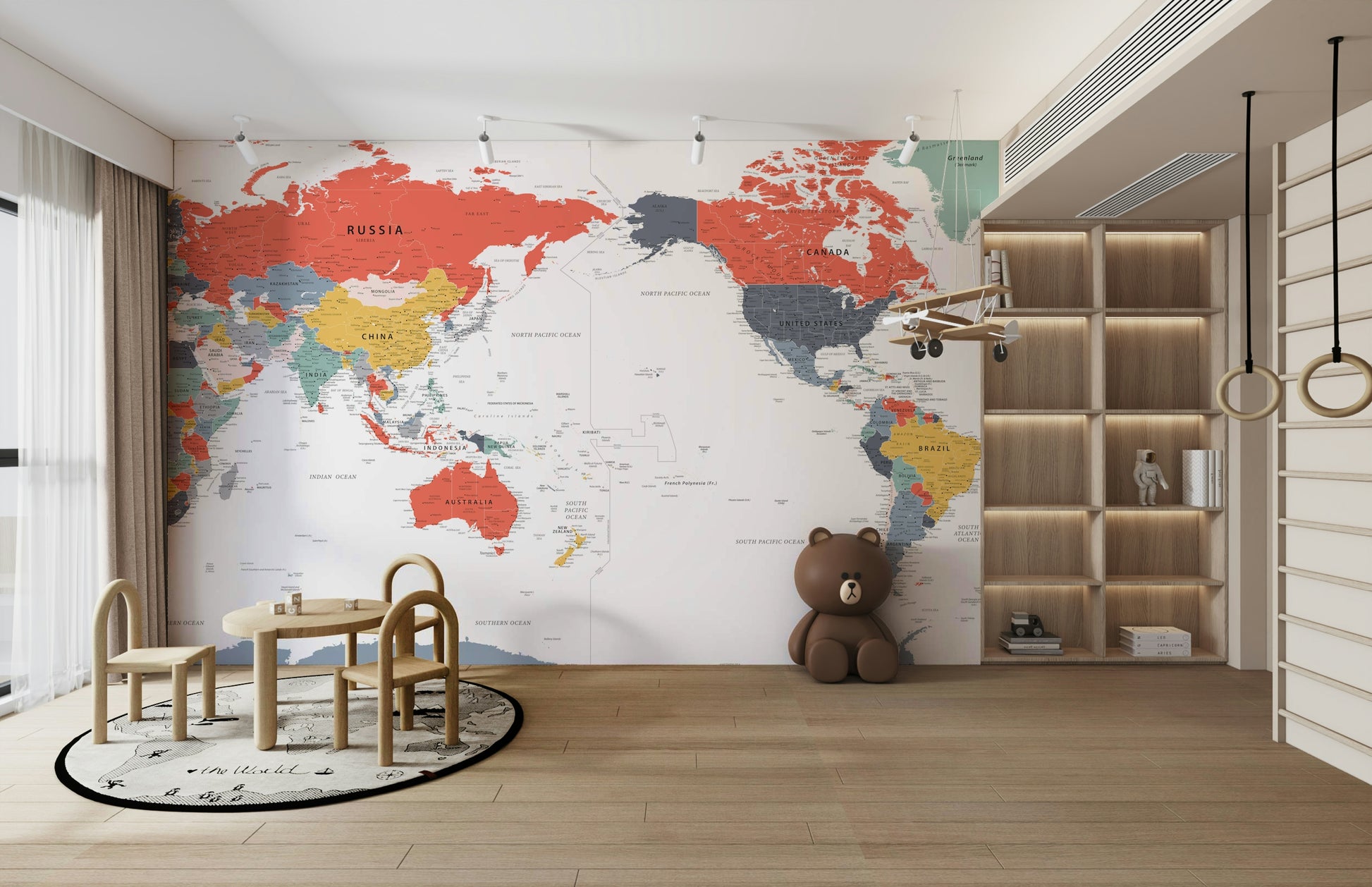 Pacific Centered World Map in Happy Colors wallpaper mural behind a wood toddler table and brown bear plush