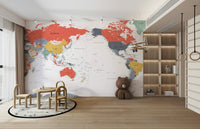 Pacific Centered World Map in Happy Colors wallpaper mural behind a wood toddler table and brown bear plush