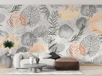 Palm tropical leaves wallpaper mural in neutral tones behind a white sofa and brown leather ottoman