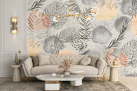 Palm tropical leaves wallpaper mural of grey and peach line-art foliage above a beige tufted sofa
