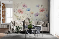 Pastel Poppy Field wallpaper mural in pink and blue behind a beige sofa with green throw in a bright living room
