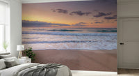 Peace at the Beach wallpaper mural of a calm sunset sea behind a white bed with a grey throw in a bedroom
