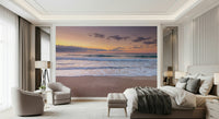 Peace at the Beach wallpaper mural of a sunset sea above a beige bed and two cream tub chairs in a bedroom