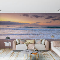 Peace at the Beach wallpaper mural of dusk surf behind a beige sofa with pink pillows and gold tables in a living room