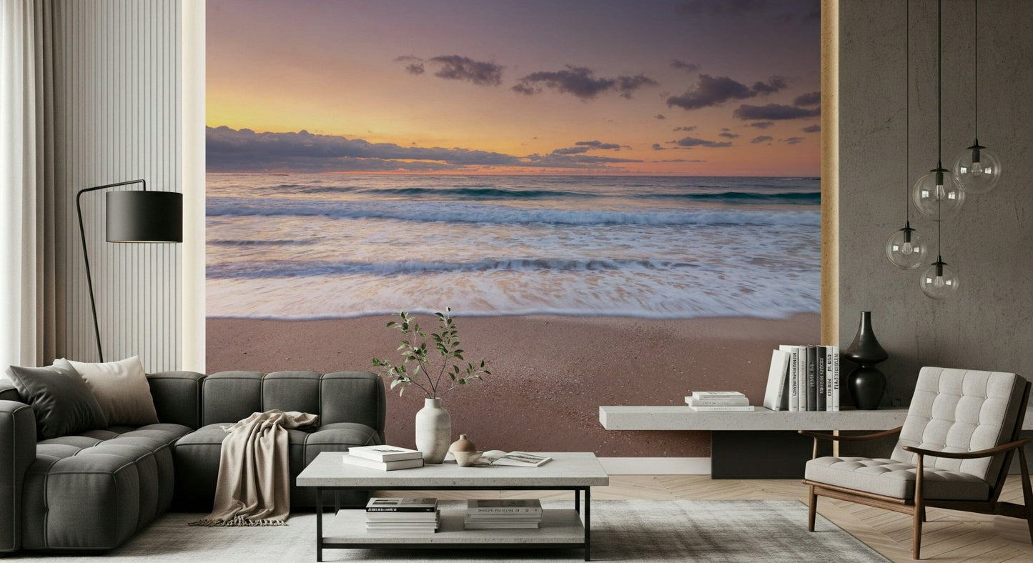 Peace at the Beach wallpaper mural of a sunset shoreline behind a dark grey sofa and white chair in a living room