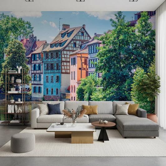 Petite France Charm wallpaper mural of Strasbourg houses behind a gray L-sectional and white shelving in a living room